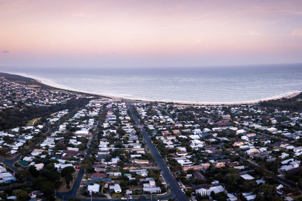 An aerial shot of Torquay City Council houses and coastline at sunset