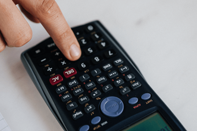 A close-up of a finger pressing a button on a black calculator.