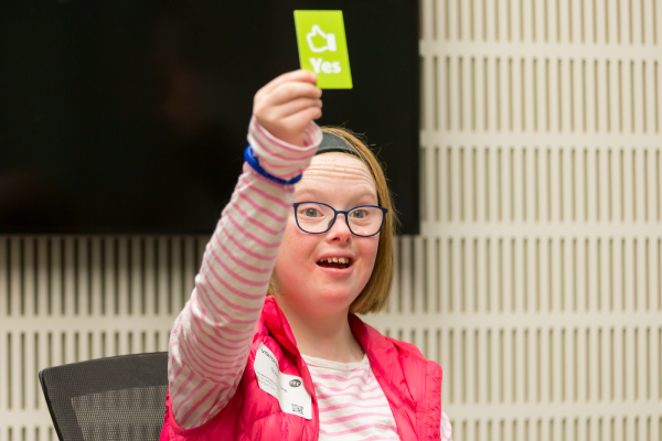 Person holding up green card with "yes" written on it