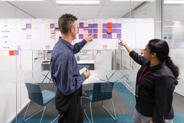 Two people talking in front of a window that is covered in sticky notes