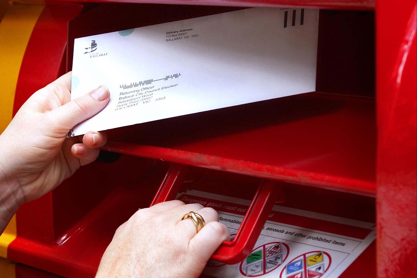 A person deposits a ballot pack in a mailbox